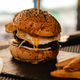 Fancy gourmet burger on square of slate with four fries